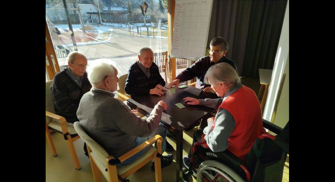 Vier Männer beim Watten an einem Tisch am Fenster, ein Mann schaut zu