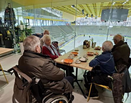 Un gruppo di anziani guarda una partita di hockey su ghiaccio seduti al tavolo del bar
