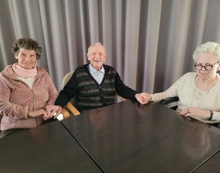 Zwei Frauen und ein Mann halten sich an den Händen