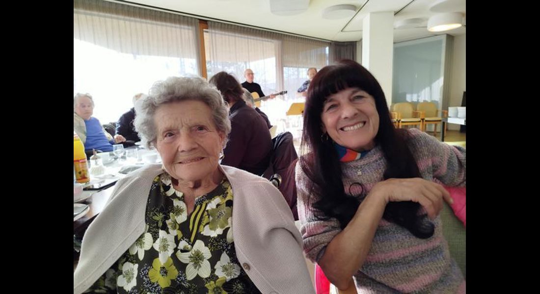 Ein Eindruck von der Geburtstagsfeier: Im Vordergrund sieht man zwei Frauen, im Hintergrund die Band, die spielt und einige andere Bewohner an einem Tisch