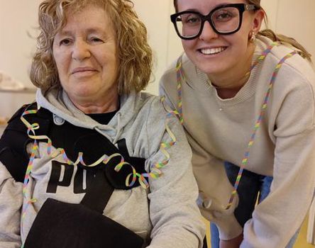 Eine Frau mit einer bemalten Hand und eine junge Frau; beide haben eine Luftschlange um